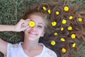 Smiling Girl in Grass with Flowers.